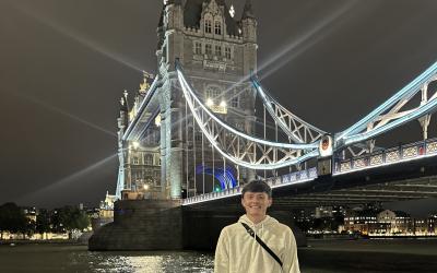 A young man stands in front of London's Tower Bridge