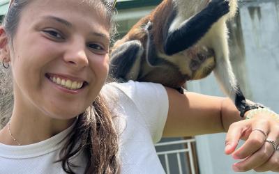 A young woman stands with a monkey on her shoulder