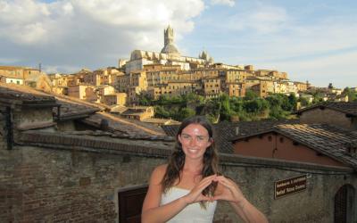 A young woman stands by a Siena skyline