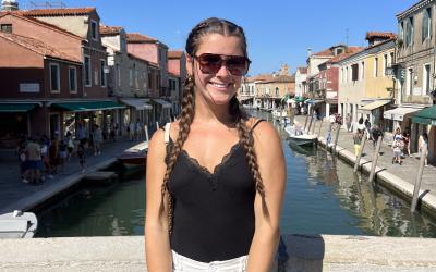 A young woman stands on a bridge in Italy