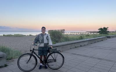 Smiling college-aged male with bicycle posing during a sunset.