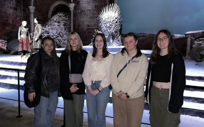 Five college students standing in front of a "Game of Thrones" set. 