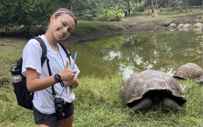 College student posing next to large tortoise.