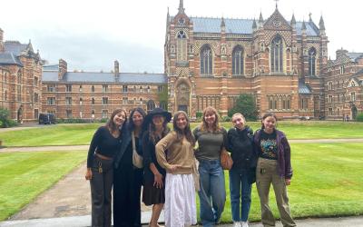 Group of seven college students posing in front of historic building.