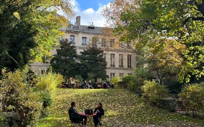 Two people sitting at a table in a clearing surrounded by trees. 