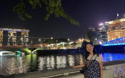 College student posing in front of the Marina Bay Sands SkyPark in Singapore at night.