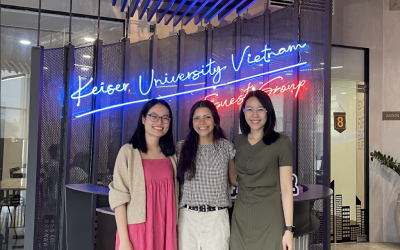 Three females posing in front of a neon sign in Vietnam. 