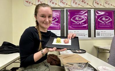 Girl holding up a plate of a homemade Japanese treat in a workshop. 