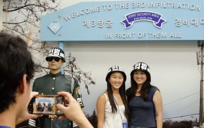 two people stand take a picture in front of a sign that reads "Welcome to the 3rd infiltration"