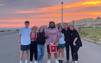 Group of eight friends posing together with a sunset in the background.