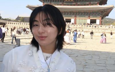 College student in traditional Korean dress in front of a temple in Seoul.