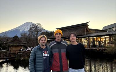 Three individuals posing for a photo with Mount Fuji in the background during sunset.