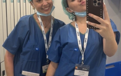 Two people in blue scrubs pose in the mirror for a picture