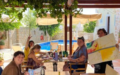 5 classmates work on their art underneath an outdoor canopy