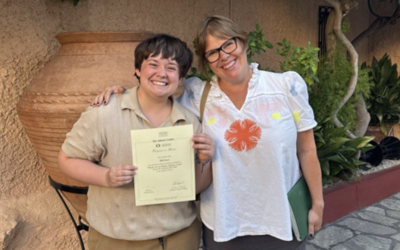 Will stands with a certificate next to someone else, they are both smiling