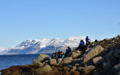 students climbing on rocks with mountains in the distance