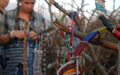 Two people standing in the background looking at bracelets on a tree