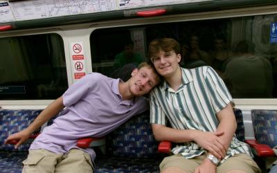 Two classmates sit on the tube together 