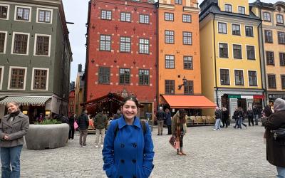 Student smiling in front colorful buildings in Stortorget, Sweden