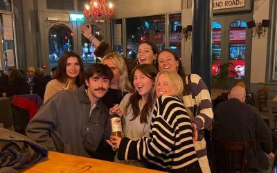 Group of seven GEO students smiling at a pub in London