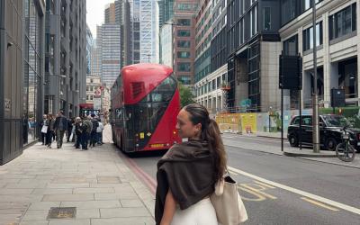 Hana walking down a street in London with a matcha in hand and a red bus in the background