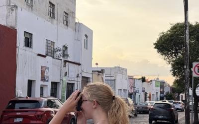 A uo student taking a picture on a camera of the streets in Queretaro