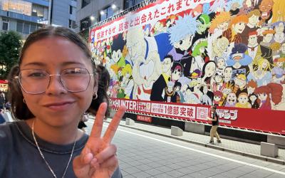 a uo student posing next to a mural of Japanese art 