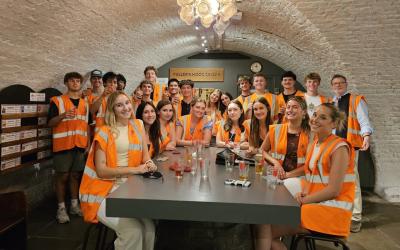 A group of UO students sitting and standing around a table wearing orange safety vests