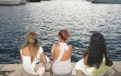 Three students sitting on the edge of a body of water