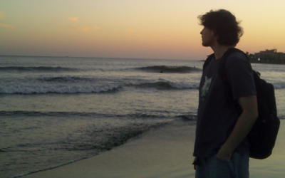 A person standing on the beach looking out at the sea
