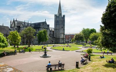 Grassy area and seating area in front of grey-brick cathedral